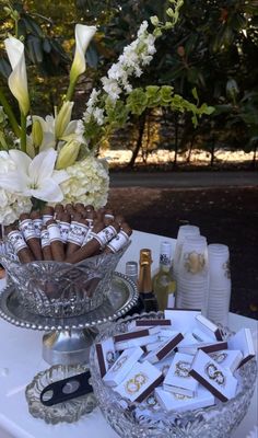 a table topped with a glass bowl filled with chocolate covered candies and white flowers