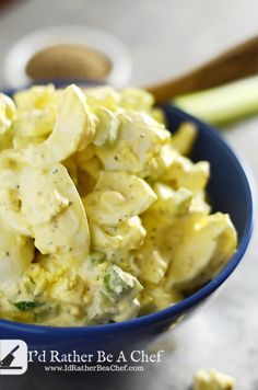 a blue bowl filled with pasta and broccoli on top of a white table