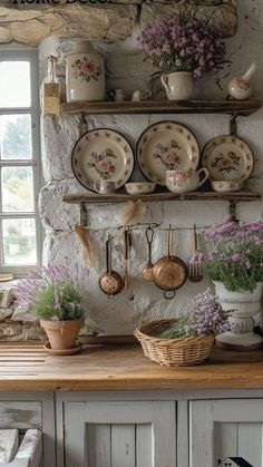 an old fashioned kitchen with pots and pans on the wall, flowers in vases