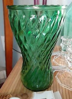 a green glass vase sitting on top of a wooden table next to some candy bars