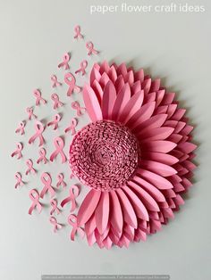 a paper flower with pink ribbons on it