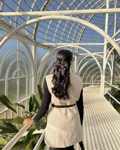 a woman in a white dress is walking down the stairs with her hair pulled back