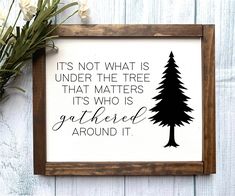 a wooden frame with a black and white print on it that says, it's not what is under the tree that matters its who is gathered around it