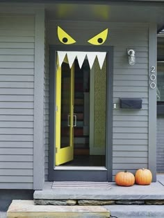 two pumpkins sitting on the front porch of a house with monster's teeth painted on it