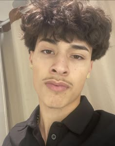 a close up of a person wearing a black shirt and gold earrings in front of a mirror