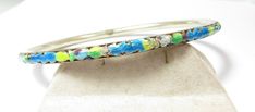 Always check out my "DEALERS SPECIAL SOCUS " Clearance Section. The bangle bracelet does have a small mark which reads silver. To make sure I tested it with nitric acid and it is solid sterling. It weighs 10.7 grams. The bracelet is 3" in diameter and will easily fit over your hand. It has a floral colorful design completely around the outside. Multicolor Enamel Bangle Bracelets, Silver Enamel Cuff Bracelet As Gift, Silver Enamel Bracelets For Wedding, Gold Pin, Stick Pins, Amethyst Earrings, Red Stone, Colorful Design, Silver Enamel