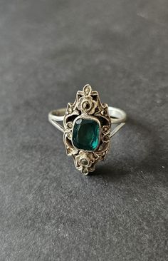 A gorgeous original Art Deco ring. Hallmarked sterling silver. A paste stone with the look of a beautiful emerald.  Studded with twinkling marcasites, with a tiny forget me not flower detail to the top & bottom. Ring size N, US size 7. The front of the ring is just over 2cm tall. Such an elegant shape ~ Art Deco Emerald Ring With Rose Cut Diamonds, Art Deco Green Emerald Ring With Rose Cut Diamonds, Vintage Green Rings With Stone Setting, Antique Green Emerald Cut Ring, Antique Green Emerald Cut Emerald Ring, Antique Green Emerald-cut Emerald Ring, Antique Emerald Cut Green Emerald Ring, Vintage Green Emerald Ring With Rose Cut Diamonds, Antique Silver May Birthstone Jewelry