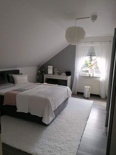 a bedroom with a bed, rugs and windows in it's attic dormer