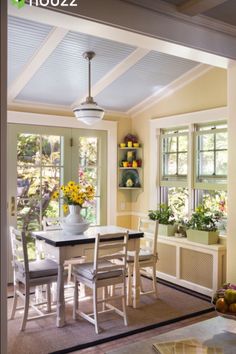 a dining room table and chairs with flowers in the vase