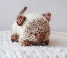 a small stuffed cat laying on top of a white blanket