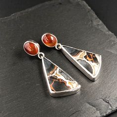 Maligano jasper and carnelian sterling silver earrings. Nice unique earring model. The stones are set with fine silver. Ear post and ear nut are sterling silver. Carnelian stones are red-orange in color. The Maligano jasper is gray veined with white, orange and crystalline inclusions. Dimensions Height: 48mm Thickness: between 4.5mm and 5.5mm Ear post: 10mm x 0.9mm Finish Shiny  Material Maligano jasper Cornaline  Sterling silver Please, do not hesitate to contact me if you have any questions. Carnelian Stone, Stone Earrings, Unique Earrings, Fine Silver, Sterling Silver Earrings, Silver Earrings, Jewelry Earrings Dangle, Dangle Drop Earrings, Dangle Earrings