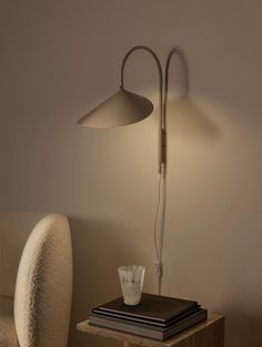 a table with a lamp on it next to a chair and a drink glass in front of the lamp