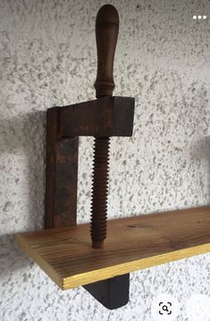 a wooden shelf with a hammer on top of it next to a wall mounted hook