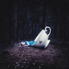 a person laying on the ground next to a large white jug in the woods with trees behind them