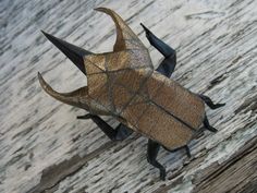 a gold and black insect sitting on top of a wooden floor