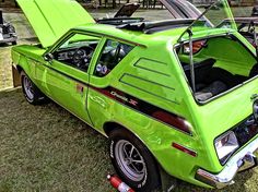 a green car parked on top of a grass covered field