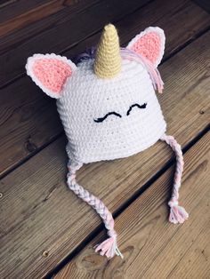 a crocheted hat with a unicorn face on it sitting on a wooden floor