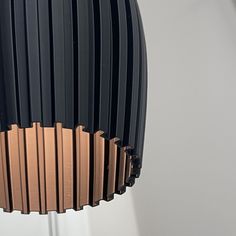 a black and gold lamp hanging from a ceiling fixture with white walls in the background