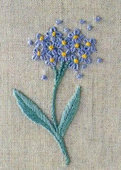 an embroidered piece of cloth with blue flowers on the bottom and yellow centers in the middle