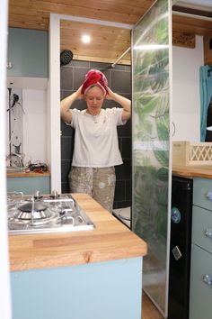 a person standing in a kitchen next to a stove top oven and sink with a towel on it's head