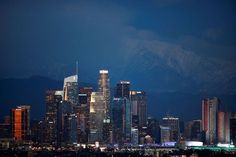 the city skyline is lit up at night with mountains in the backgrouund