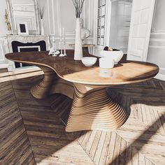 a wooden table sitting on top of a hard wood floor next to a white vase