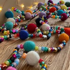 a bunch of beads that are laying on a wooden table with lights in the background