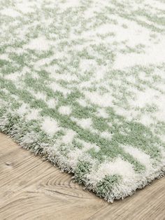 a green and white rug on top of a wooden floor next to a hardwood floor