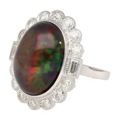 10.08 Carat Black Oval Cabochon Cut Opal with Baguette and Round Cut Diamond on 18k White Gold Ring. Open back setting and a smooth polished finish.  Details:  Item Type: Women's Ring Metal: 18K White Gold Weight: 7.38 Grams Ring Size: 7  Center Stone Details: Type: Natural Opal Carat: 10.08 Carat Color: Black (multi-color display) Cut: Oval Cabochon   Side Stones Details:  Diamond: 2pcs 0.40 CTTW Baguette Cut  Diamond: 14 pcs 1.09 CTTW Round Cut Luxury Oval Opal Ring With 17 Jewels, Luxury Opal Ring With Oval Cabochon And Polished Finish, Luxury Polished Opal Ring, Oval Cabochon, Luxury Polished Opal Ring With Oval Cabochon, Elegant Oval Opal Ring With Polished Finish, Modern Formal Opal Ring With Cabochon, Formal Modern Opal Cabochon Ring, Modern Formal Cabochon Opal Ring, Formal Opal Ring