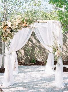 an outdoor wedding ceremony with white drapes and flowers