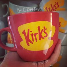 a hand holding a red and yellow coffee cup with the words yirs on it