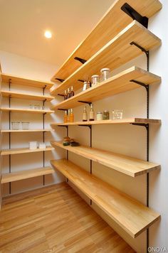 an empty pantry with wooden shelves and wood flooring on the walls, along with other open shelving units