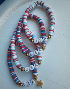 three bracelets with beads and charms on top of a white table next to a wall