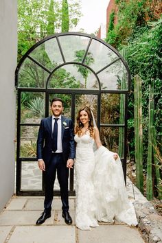 a bride and groom pose for a photo in front of an arch at their wedding