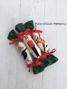 three rolls of candy wrapped in green and red ribbon on top of white wooden boards