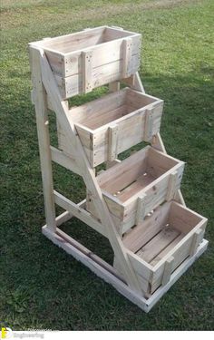 three wooden crates stacked on top of each other in the grass, with one being used as a planter