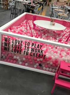 a pink table and chairs in a room filled with balloons that say we love to play, we love to work, we love to create