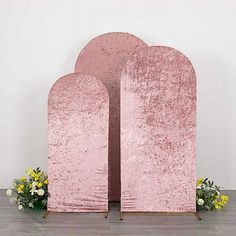 two pink sculptures sitting next to each other on a wooden floor in front of a white wall