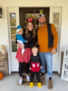 a man, woman and two children standing in front of a door with mickey mouse ears on