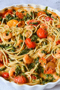 a pasta dish with shrimp, spinach and tomatoes