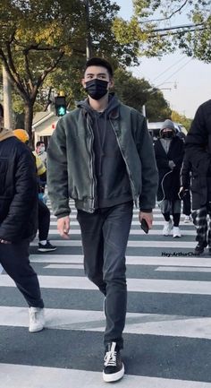 a man wearing a face mask crosses the street in front of other people on crosswalks