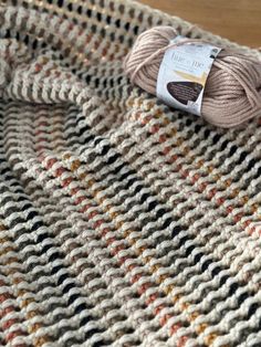 a ball of yarn sitting on top of a knitted table cloth next to a skein of yarn