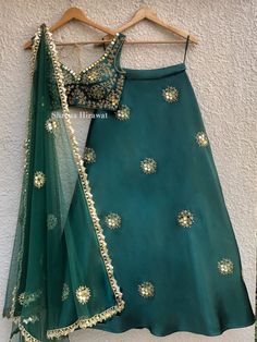 This emerald green blouse and lehenga in threadwork and sequins work embroidery is perfect for a mehendi or cocktail event.  It is teamed with a green net dupatta with gold border work and scattered butis.