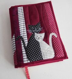 a red book with white polka dots and black cats on the cover, sitting on a table