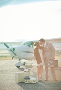 two people kissing in front of an airplane