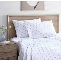 a bed with white sheets and flowers on the headboard next to a night stand