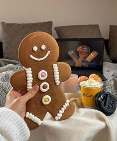 a person is holding up a gingerbread man in front of a table with drinks and snacks