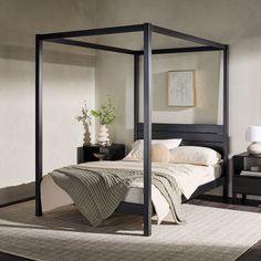 a four poster bed in a bedroom with white walls and beige carpeted flooring