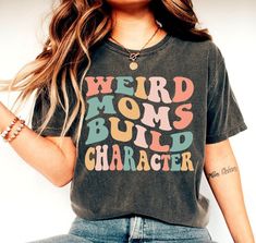 Weird Moms Build Character Shirt, Groovy Weird Mom Tee Gift, Funny Mama Shirt, Mom Life Shirt, New Mom Shirt, Trendy Mom Shirt, Cool Mom Tee We create custom t-shirts with great designs for everyone's liking. If you don't find the size or color you would like, please message us and we will be happy to accommodate! PRODUCT We use the finest premium Bella Canvas shirts for you, they are feather soft and very breathable with a good stretch. These t-shirts are known for their great quality and much loved by our consumers. SIZING This t-shirt comes in UNISEX sizing. It looks great on both men and women, but women are recommended to order a size down for a fitted look! Please refer the sizing chart to find your perfect fit! COLORS Colors on screen and the printed product may slightly vary due to Trendy Multicolor Shirt With Letter Print, Funny Multicolor Relaxed Fit Tops, Casual Multicolor Tops With Funny Text, Trendy Long Sleeve Tops With Funny Text, Cute Multicolor Tops With Funny Text, Multicolor Letter Print Tops With Relaxed Fit, Trendy Cotton Shirt With Funny Text, Trendy Multicolor Top With Slogan, Casual Multicolor Top With Slogan