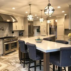 a large kitchen with an island in the middle and several chairs around it, along with stainless steel appliances